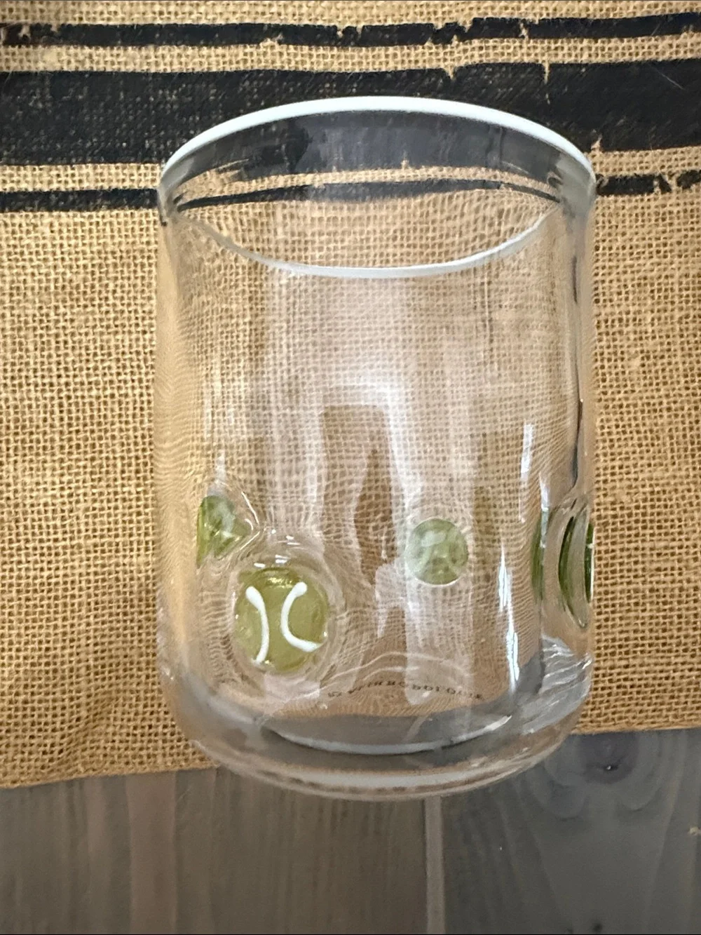 Anthropologie Clear drinking glass with yellow/green tennis ball accents.